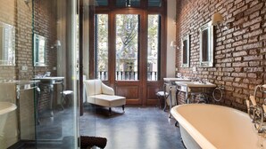 Ein modernes Badezimmer mit einer großen Badewanne, einer gläsernen Dusche und einem weißen Sessel.