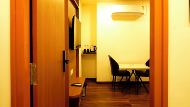 A narrow hallway leading to a dining area with a table and chairs, a microwave, and a small shelf with items. - sithara inn by revtree (Hospet)