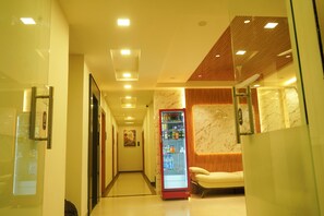 A hotel corridor with a vending machine, a seating area, and a mirror on the wall. - sithara inn by revtree (Hospet)