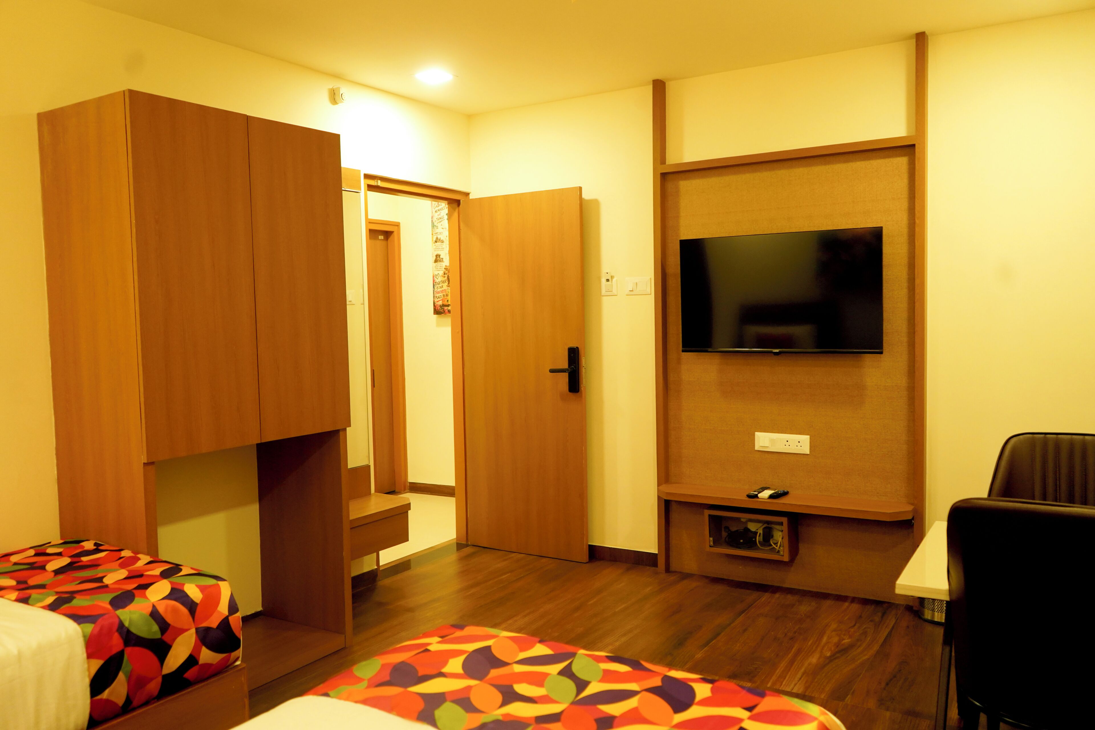 A hotel room with a bed, a TV mounted on the wall, and a wardrobe.