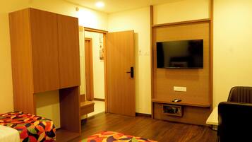 A hotel room with a bed, a TV mounted on the wall, and a wardrobe.