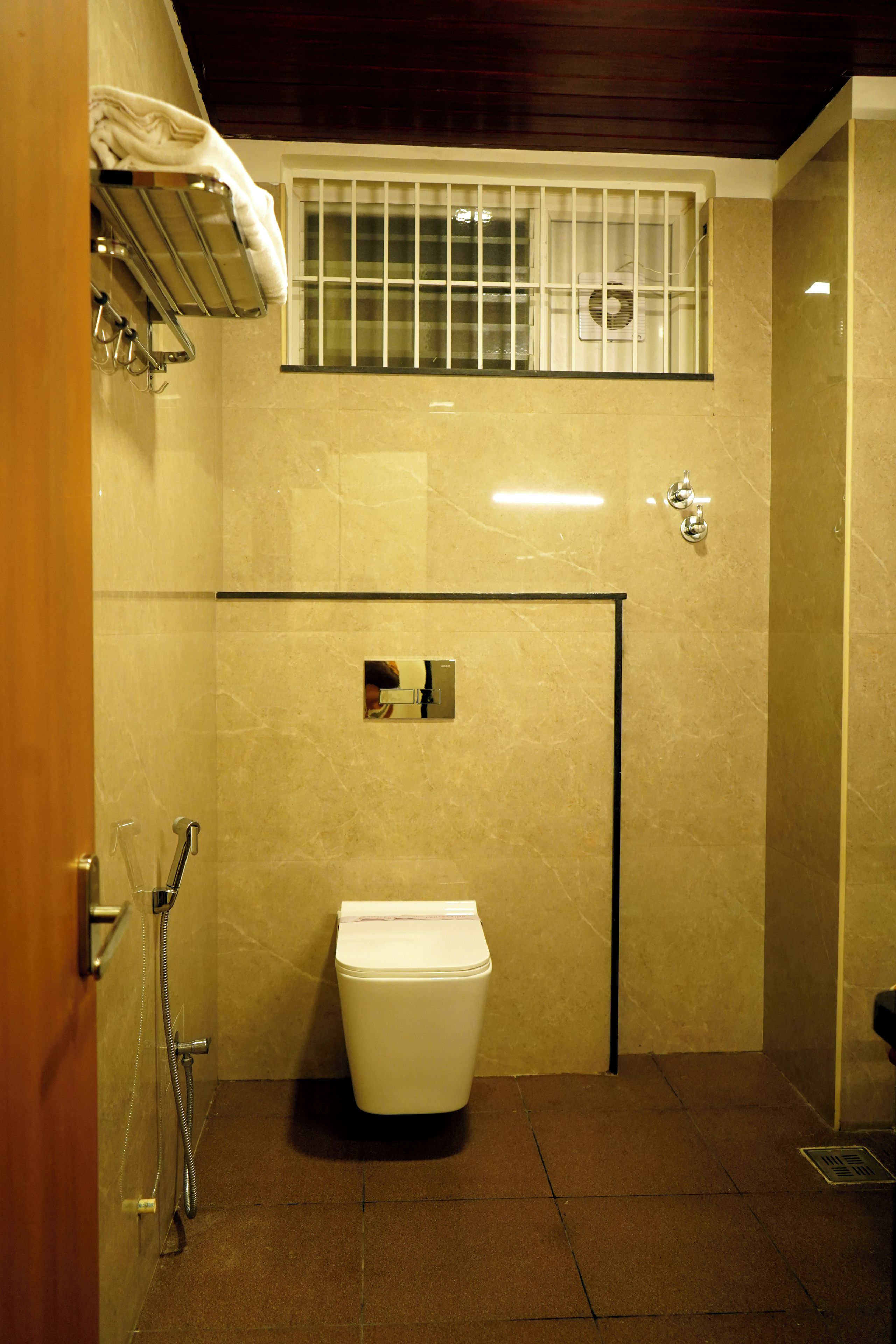 A small bathroom with a toilet, a shower, and a towel rack.