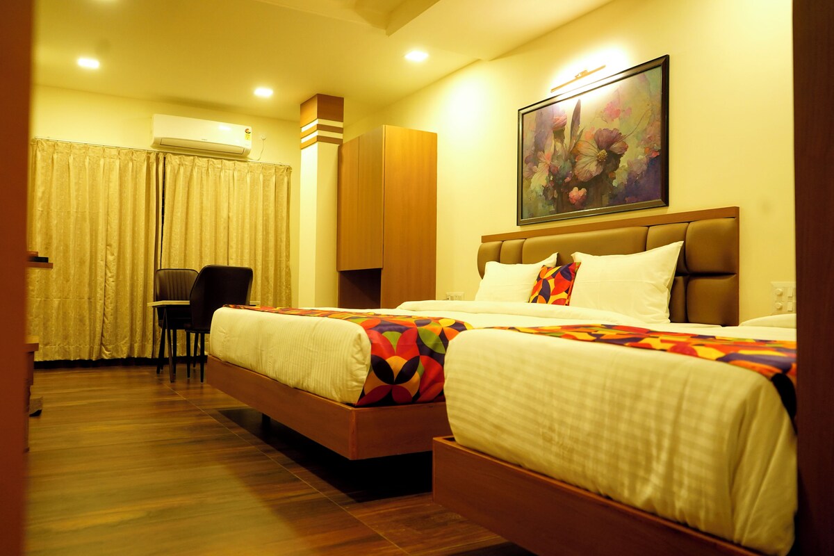 A hotel room with two beds, a desk, and a chair.