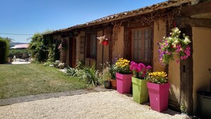 A rustic building with a gravel driveway, potted plants, and a clear blue sky. - Charming gite with a private pool in the French countryside (Saint-Étienne-de-Fougères)