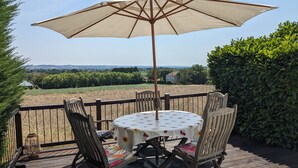 An outdoor patio with a round table, four chairs, and a large umbrella. - Charming gite with a private pool in the French countryside (Saint-Étienne-de-Fougères)