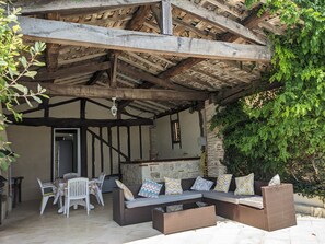 Ein Außenbereich mit Holzdecke, einer Sofagarnitur und einem Tisch mit Stühlen.