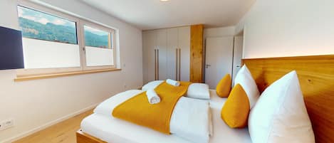 A modern bedroom with a bed, wooden headboard, and a window with a view.