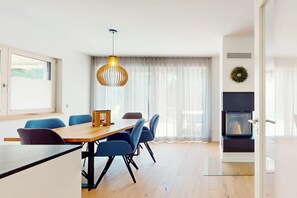 A modern dining area with a wooden table, blue chairs, and a hanging pendant light. - Chalet AlpspitzBlick – Alpine Chalet with Sauna & Garden, Garmisch-Partenkirchen (Garmisch-Partenkirchen)