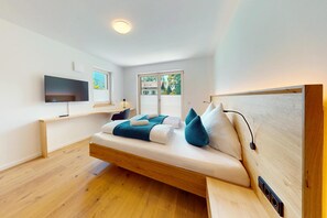 Une chambre moderne avec un lit, une télévision et une fenêtre donnant sur un paysage verdoyant.