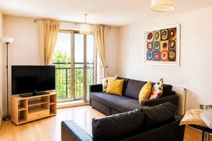 A modern living room with a flat-screen TV, a sofa, and a coffee table. - Modern Brindley Point Apt, Near Canals & Broad (West Midlands)