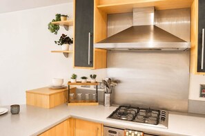 A modern kitchen with stainless steel appliances, wooden cabinets, and a built-in stove. - Modern Brindley Point Apt, Near Canals & Broad (West Midlands)