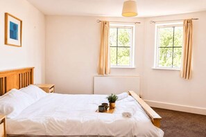 A bedroom with a bed, bedside tables, a window, and a hanging light fixture. - Modern Brindley Point Apt, Near Canals & Broad (West Midlands)