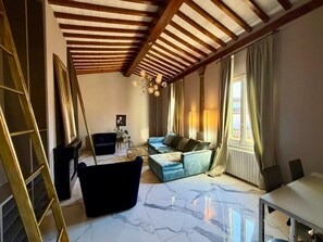 Ein geräumiges Wohnzimmer mit hoher Decke, einer Sofagarnitur, einem Couchtisch und einem Essbereich.