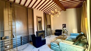 A spacious living room with a high ceiling, a fireplace, a sofa set, and a ladder against the wall. - Vigna Luxury Florence (Firenze)