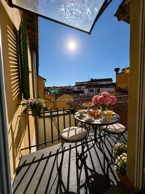 Ein Balkon mit Frühstückstisch, einem Blumentopf und Blick auf die Stadt.