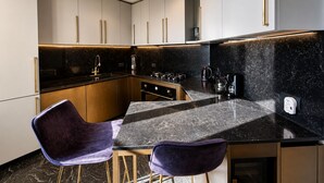 A modern kitchen with a black marble countertop, gold handles, and a built-in stove. - Vigna Luxury Florence (Firenze)