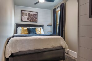 A bedroom with a bed, a ceiling fan, a framed picture on the wall, and a window with curtains. - 300 Feet from Outlaw Square. 9 Shine is the best vacation rental in Deadwood. (Deadwood)