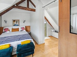 A bedroom with a large bed, a wooden ceiling, and a view to a balcony.