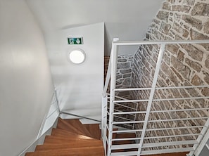A staircase with a white railing, a wooden handrail, and a stone wall. - Charming two-story apartment in the heart of Pont-Aven (Pont-Aven)