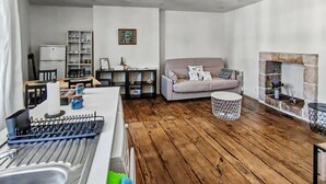 Una sala moderna con un sofá, un comedor con una mesa y sillas, una cocina con un fregadero y utensilios, y una chimenea.