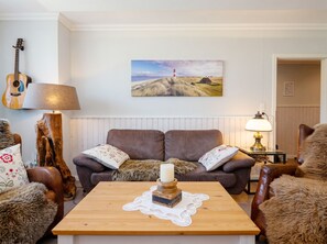 A living room with a wooden coffee table, a brown sofa, and a guitar against the wall. - Käpt n Stuv: Your cozy family vacation home near the beach in Büsum (Büsum)