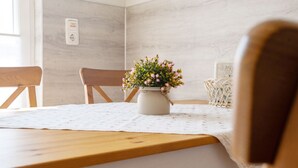Et spisebord med blomsterarrangement, træstole og et hvidt borddække.