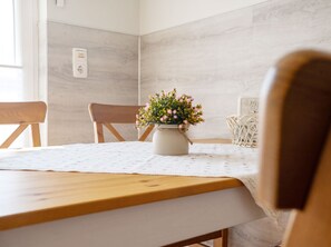 A dining table with a floral centerpiece, wooden chairs, and a white tablecloth. - Käpt n Stuv: Your cozy family vacation home near the beach in Büsum (Büsum)