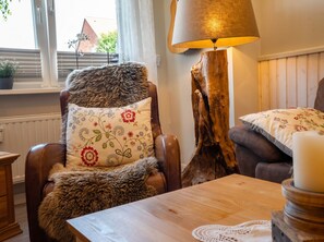 A cozy room with a leather armchair, a wooden coffee table, and a lamp. - Käpt n Stuv: Your cozy family vacation home near the beach in Büsum (Büsum)