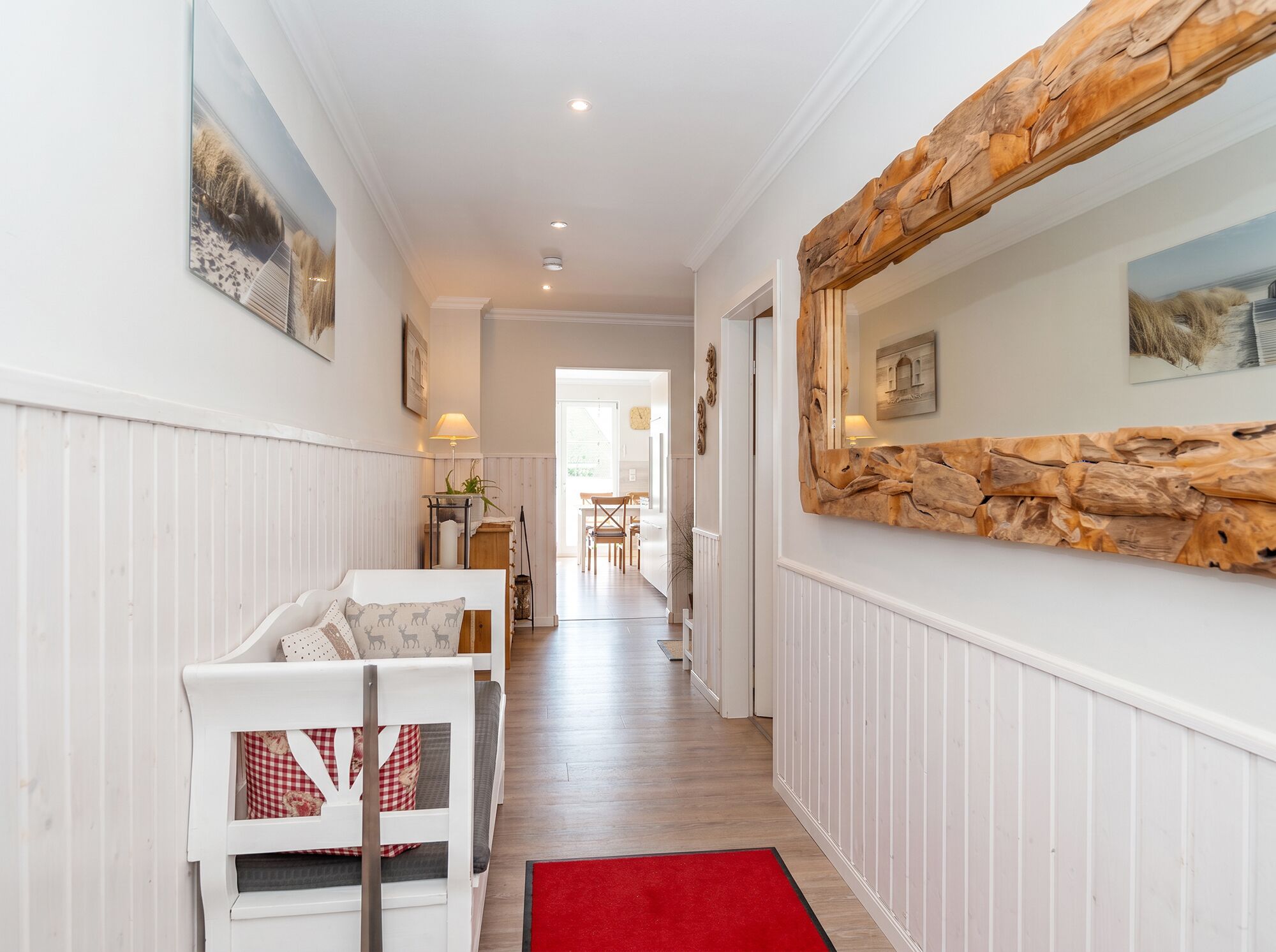 A hallway with a white sofa, a red rug, and a wooden wall feature.
