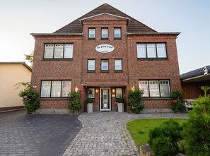 A two-story brick building with a central entrance, multiple windows, and a sign indicating it was built in 1942. - Käpt n Stuv: Your cozy family vacation home near the beach in Büsum (Büsum)
