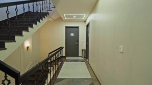 A staircase with a black railing leading to a door with a light fixture above it. - Hotel Pinaki Inn (Ujjain)