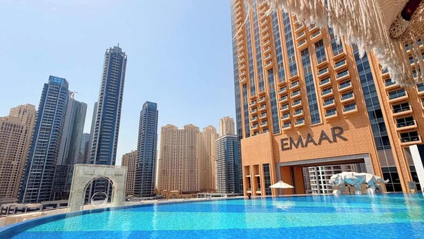 A hotel with a pool, surrounded by high-rise buildings, and the name 'EMAR' visible on the facade. - Chic 1BR at JW Marriott Hotel, Dubai Marina (Dubai Marina)