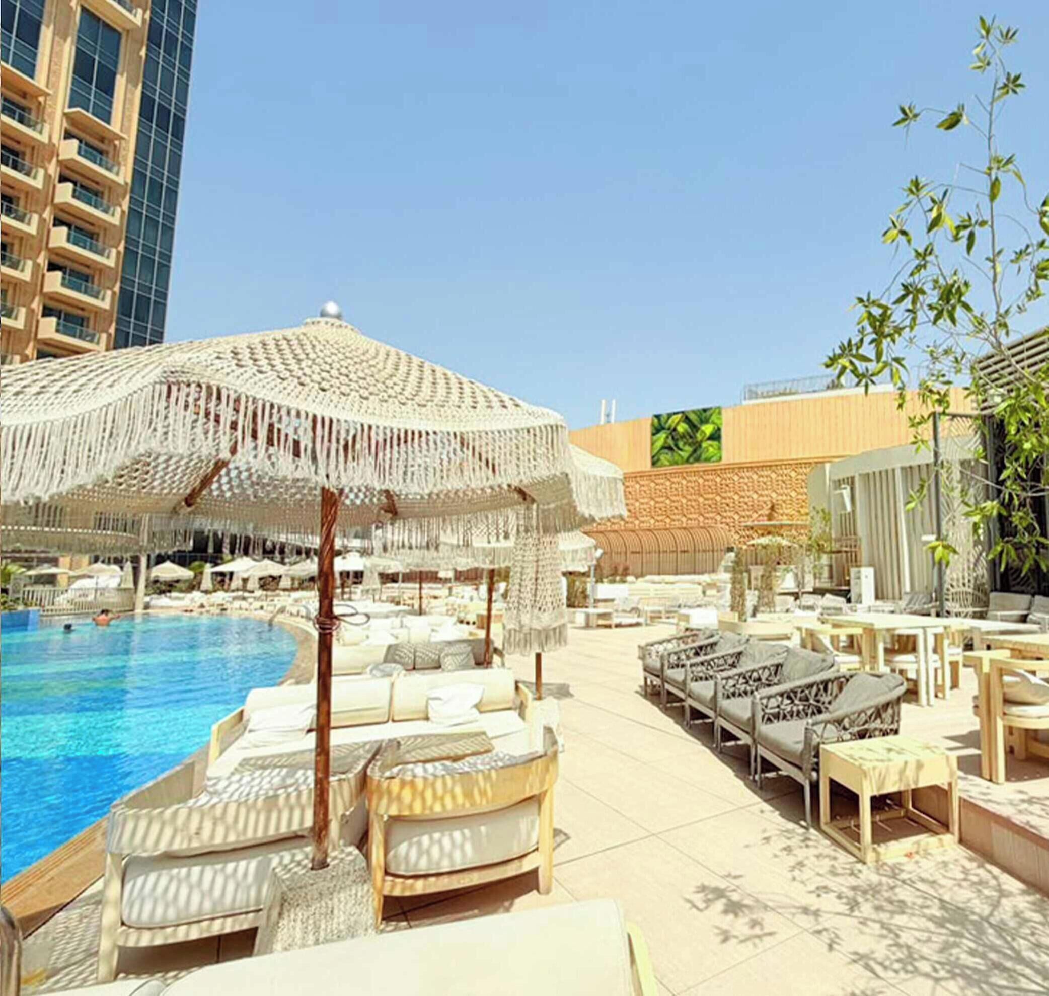 A poolside area with lounge chairs and a large woven umbrella.