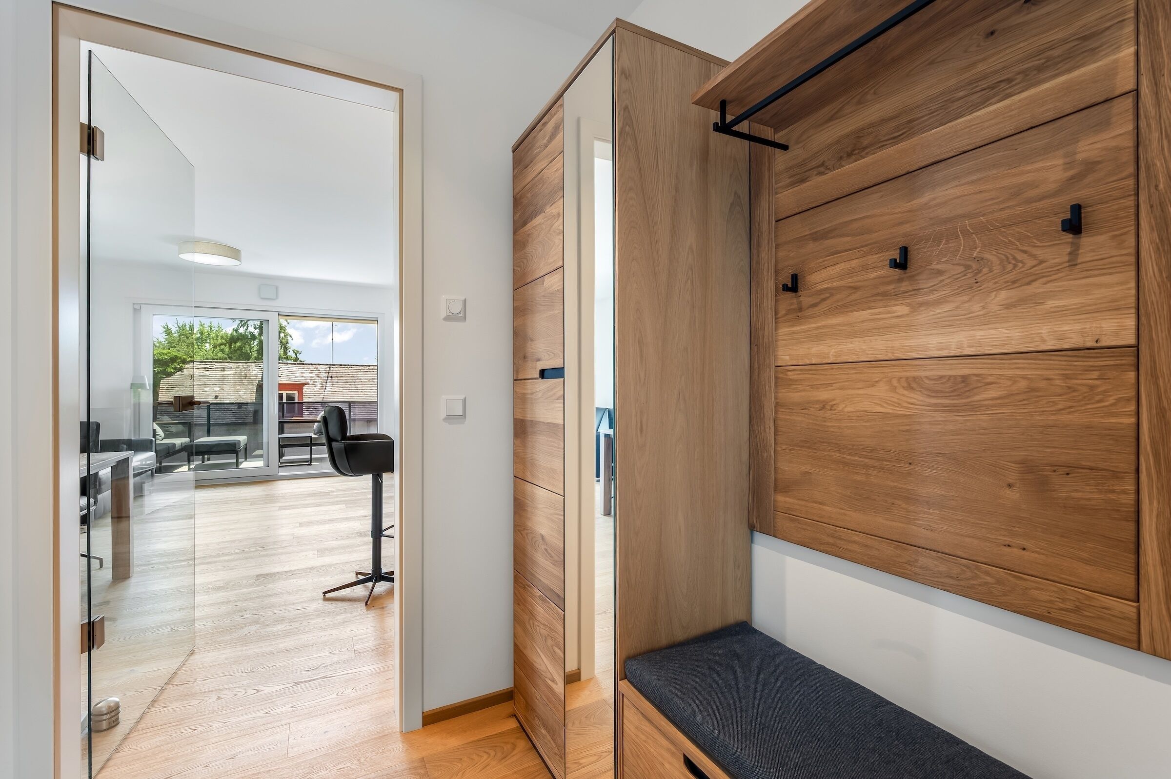 Un interno moderno con una panca in legno, una porta vetrata che dà su un patio e un design minimalista.