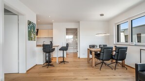 Una cocina moderna con suelo de madera, un comedor con sillas negras y un ventanal grande.