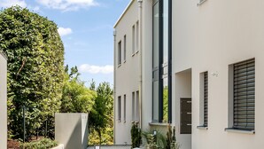 Un edificio moderno con ventanas amplias y fachada plana, rodeado de vegetación.