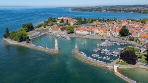 Un pueblo costero con un puerto deportivo, edificios históricos y una torre destacada.