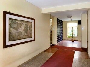 A hallway with a framed artwork on the wall, a potted plant, and a door leading to another room. - 3Bed Flat Priv Parking Metro 4min Walk (Roma)
