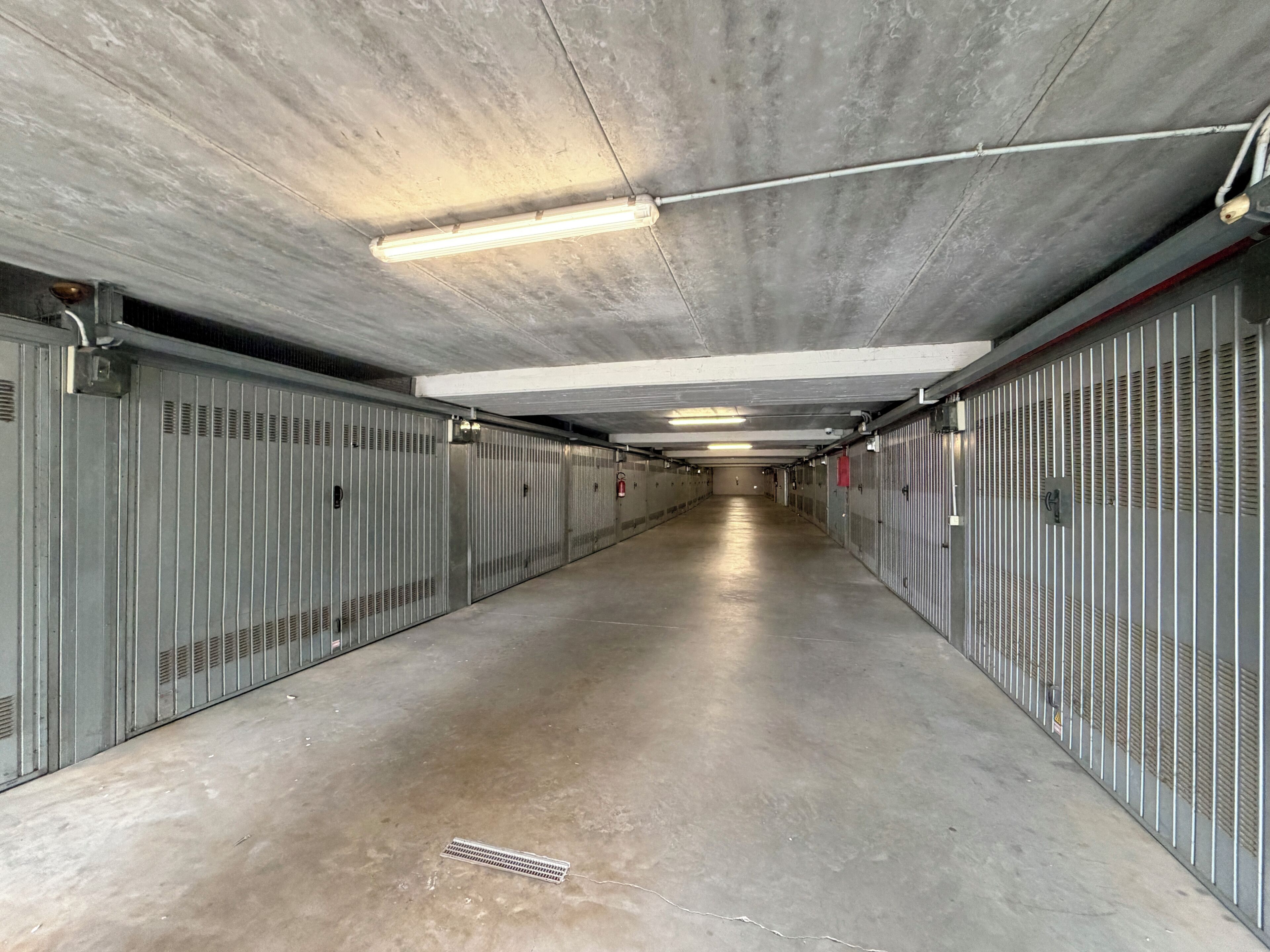 A long, narrow corridor with metal lockers on both sides and a concrete floor.