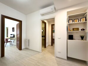 A room with a desk, chair, radiator, and a shelf with framed pictures. - 3Bed Flat Priv Parking Metro 4min Walk (Roma)