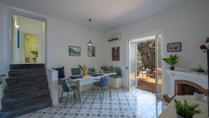 A dining area with a table set for four, a staircase leading to a bathroom, and a fireplace. - Casa Albachiara Waterfront Just Steps From the Beach (Praiano)