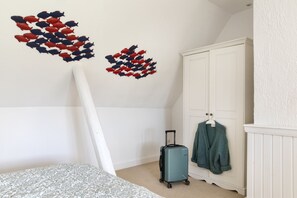 Ein Schlafzimmer mit einem Bett, einem Kleiderschrank, einem Koffer und zwei Wandbildern.