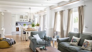 Ein großzügiger Wohnbereich mit grauem Sofa, einem Holztisch und einem Esstisch mit Stühlen.