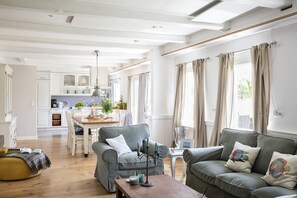 Ein großzügiger Wohnbereich mit grauem Sofa, einem Holztisch und einem Esstisch mit Stühlen.