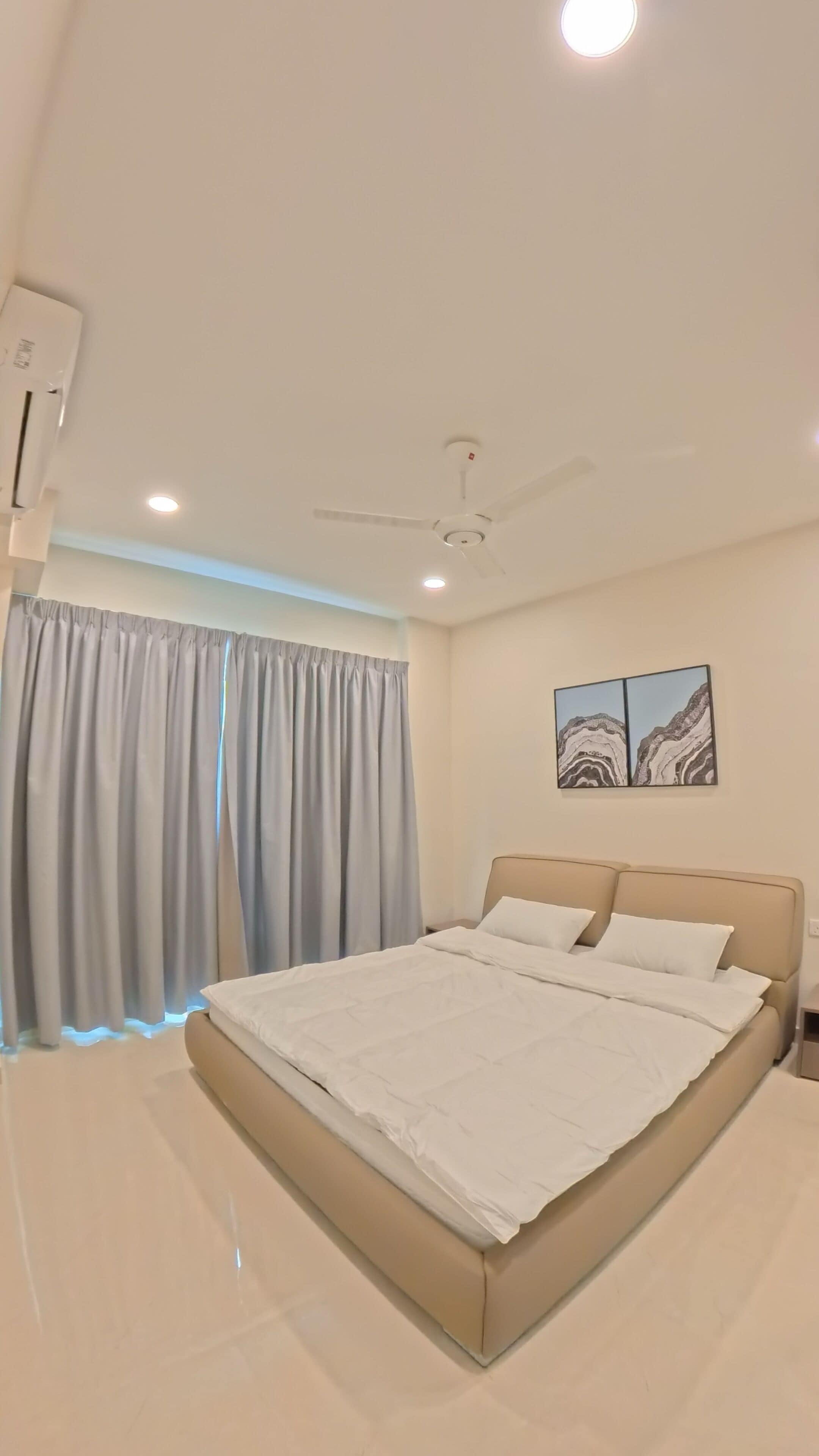 Un dormitorio moderno con cama, cortinas, ventilador de techo y una obra de arte en la pared.