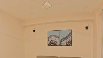 A bedroom with a large bed, a ceiling fan, and a wall-mounted artwork.