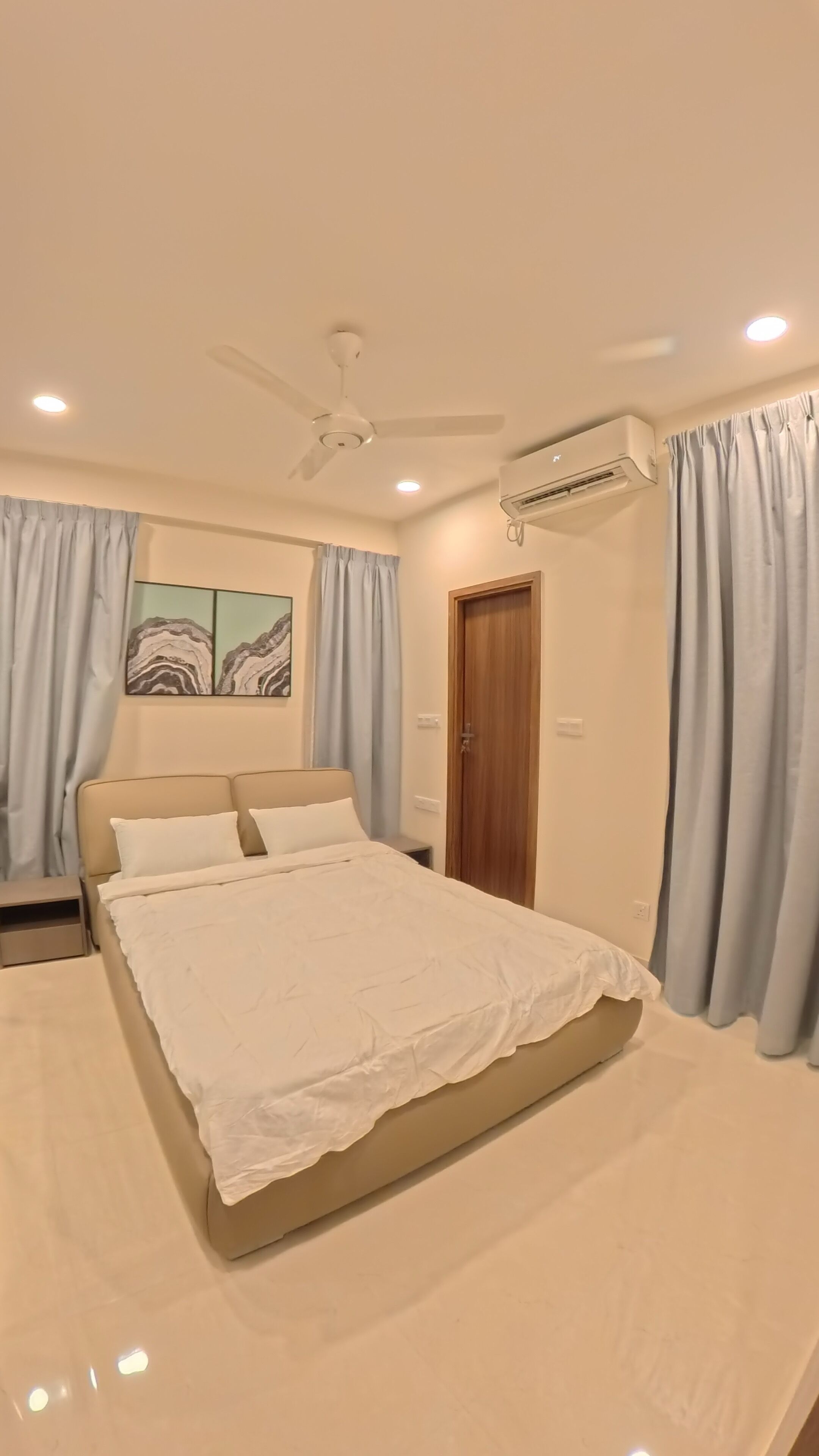 Un dormitorio con cama, ventilador de techo, aire acondicionado y cortinas claras.