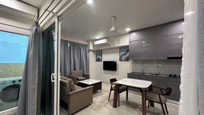 Ett modernt pentry med inbyggd ugn och mikrovågsugn, en matplats med ett bord i marmor och en soffa med utsikt över balkongen.