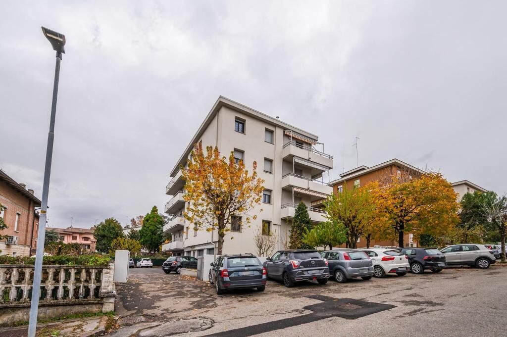 A multi-story residential building with a parking lot in front.
