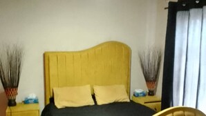 Een slaapkamer met een bed, nachtkastjes, een plafondventilator en een raam met gordijnen.